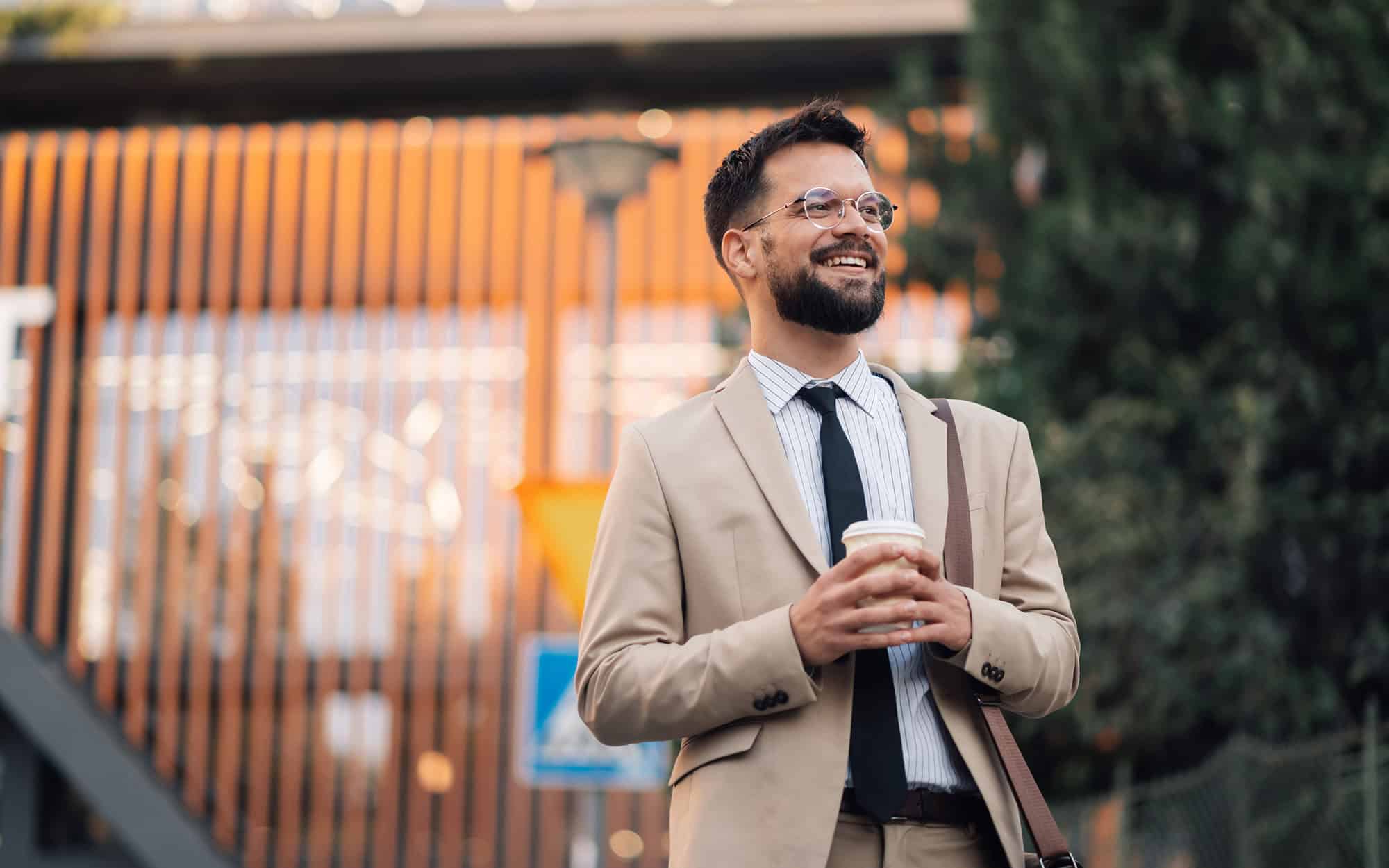 Happy Businessman Holding Coffee Walking Outside Office Building