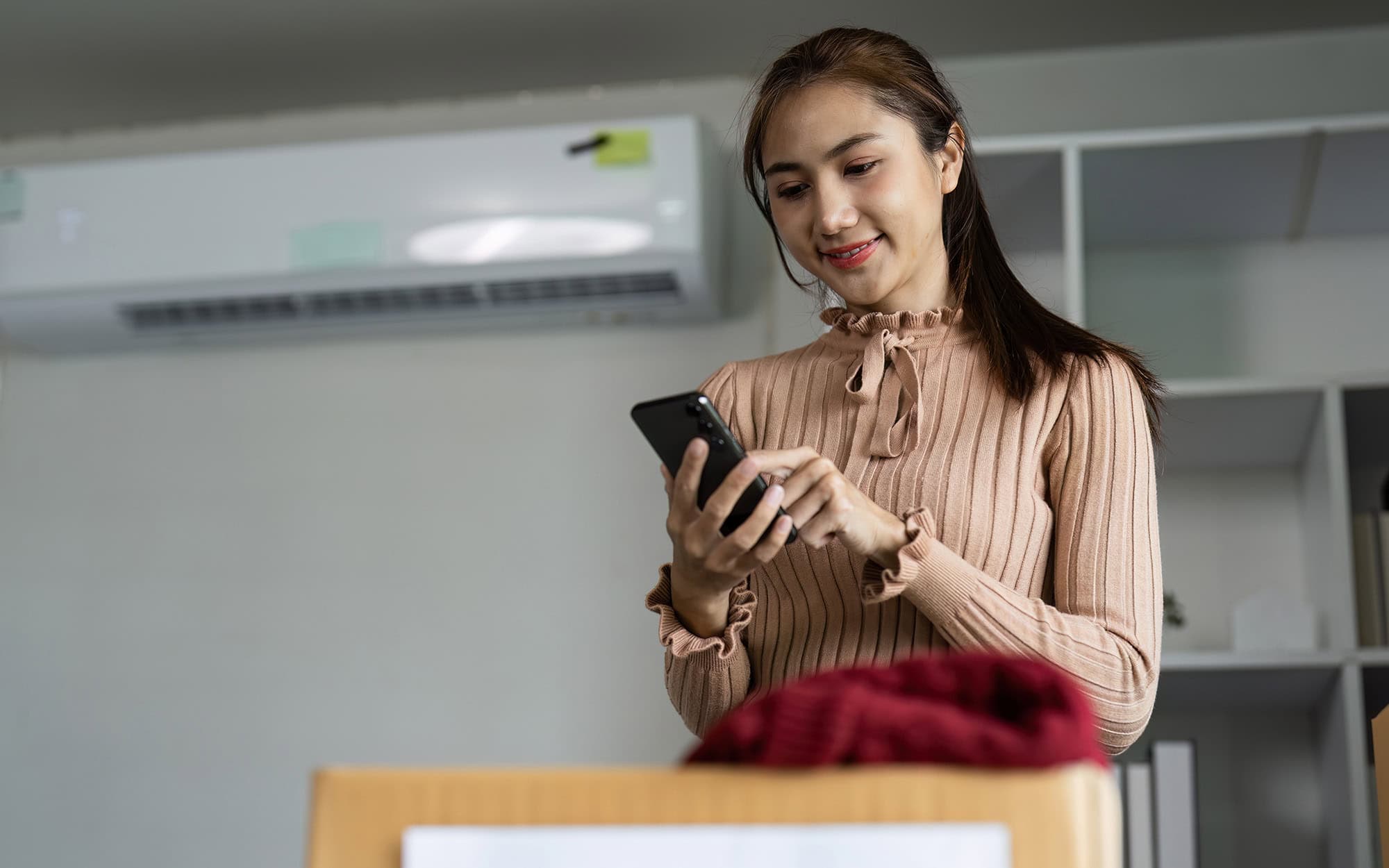 Young Woman Organizing Clothing Donations In Modern Office With Recycling Symbol On Box