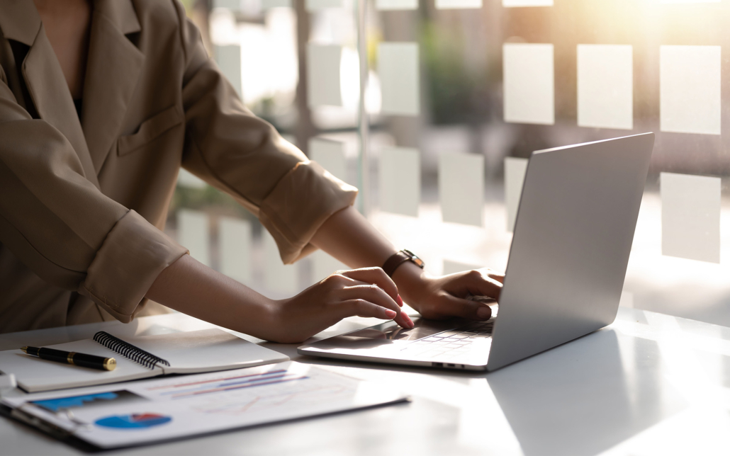Businesswoman Sitting On A Laptop Computer With Documents On The Desk In The Office