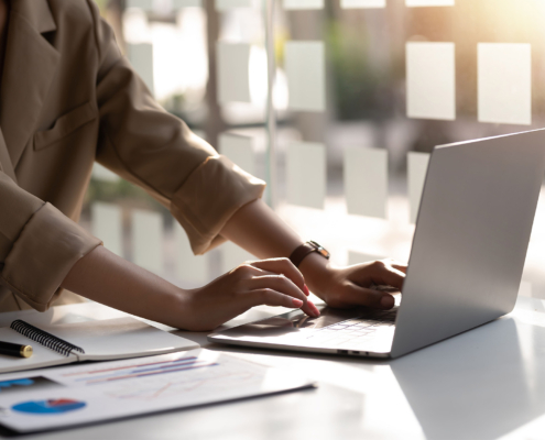 Businesswoman Sitting On A Laptop Computer With Documents On The Desk In The Office