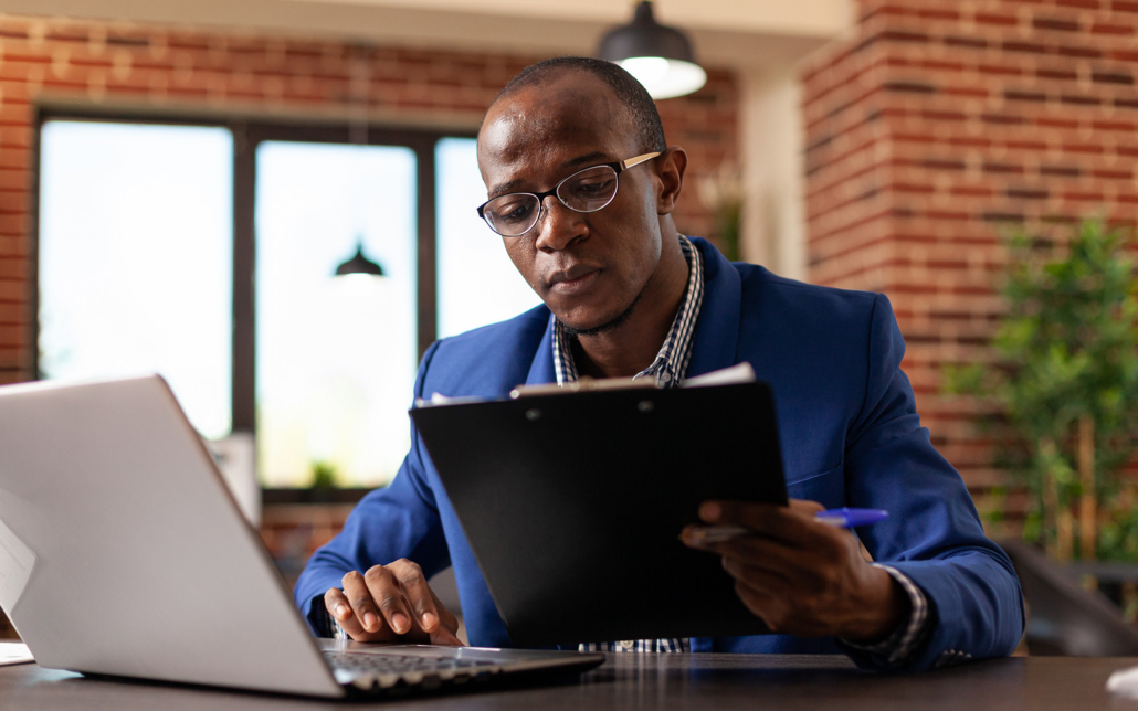 Entrepreneur Working With Laptop And Files On Clipboard To Plan