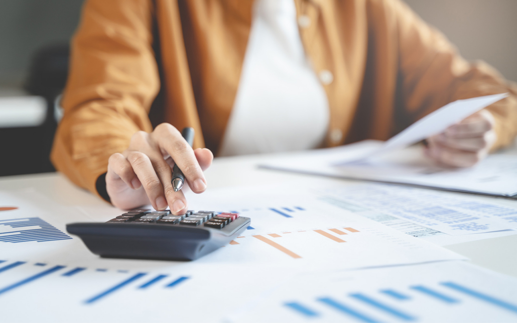 Person Doing Taxes At Desk With Calculator