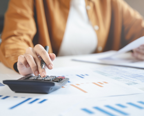 Person Doing Taxes At Desk With Calculator